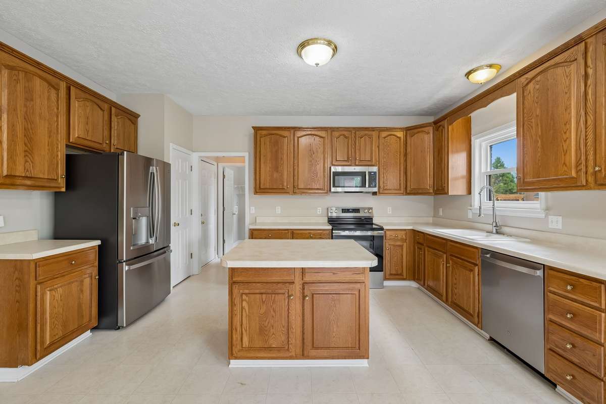 This Kitchen is full of cabinets for plenty of storage areas, all new GE Appliances that will remain (purchased in 2025), a center island that will seat two, a pantry closet and leads to the Laundry or Garage through the doorways!