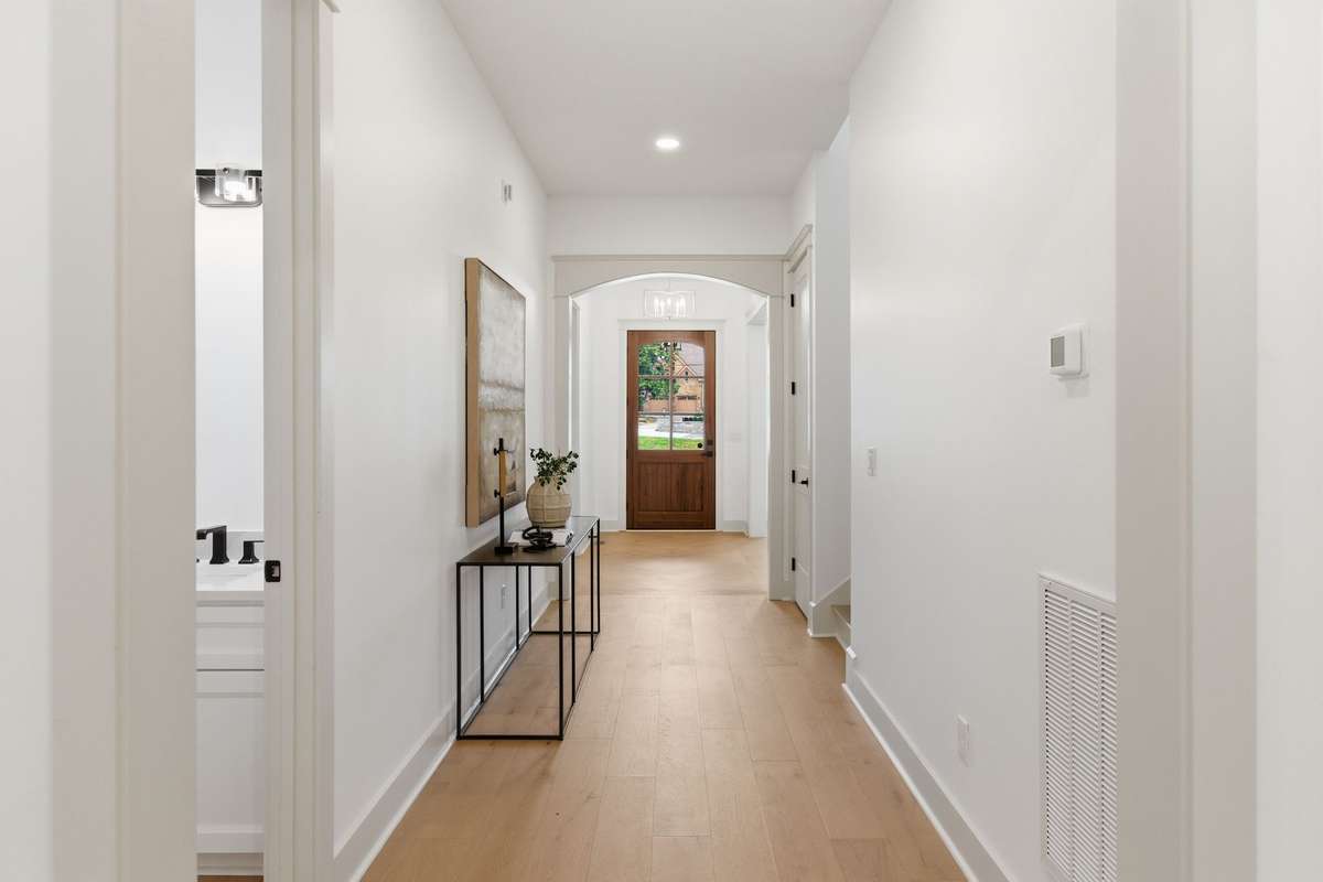 POV: From living room area looking through front hall to foyer. Powder room on left.