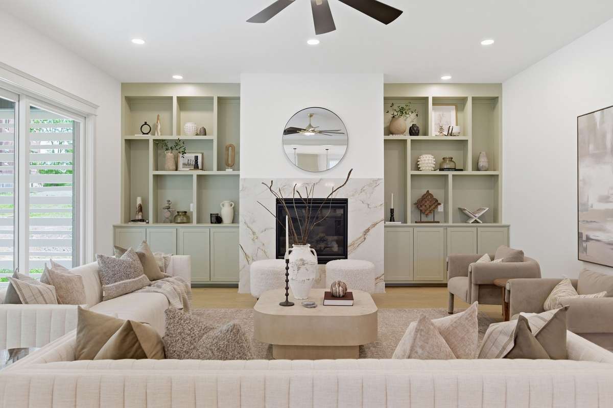 Living room off breakfast room and kitchen featuring built in bookcases and large gas fireplace and stone surround