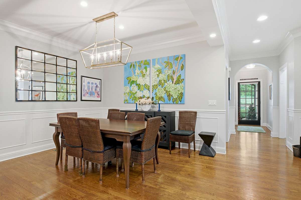 Elegant dining room w/lighted ceiling feature, wainscoting, modern chandelier