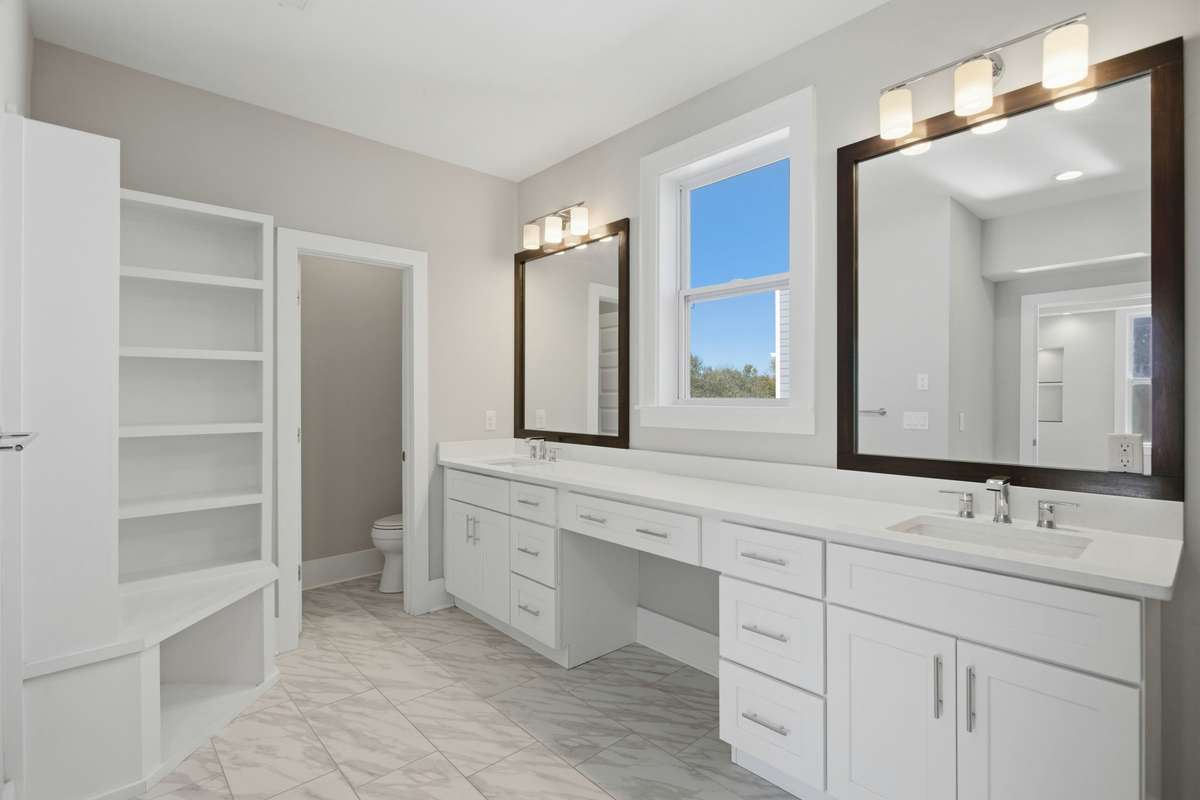 Spacious primary ensuite with double vanities, tile flooring, and a large walk-in tiled shower.
