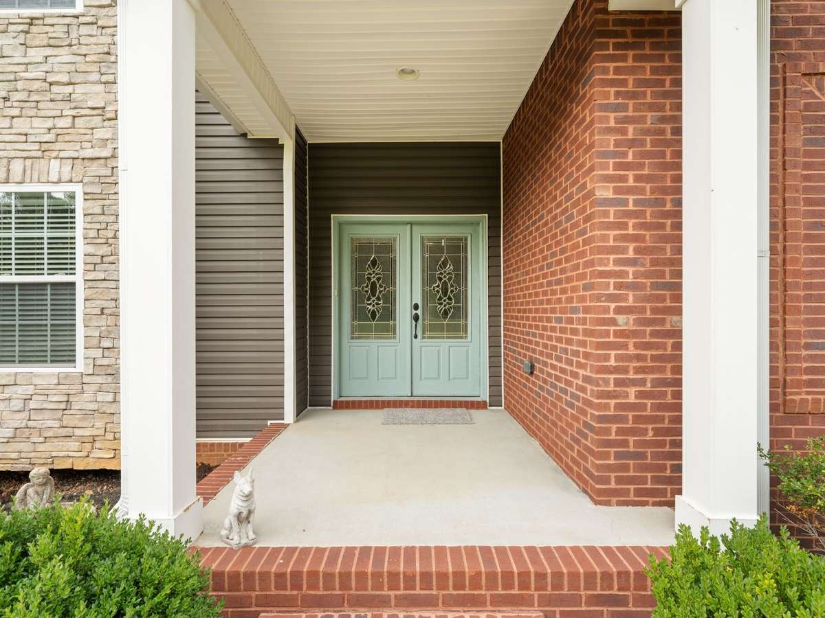 Inviting covered front porch with brick accents and welcoming entryway.