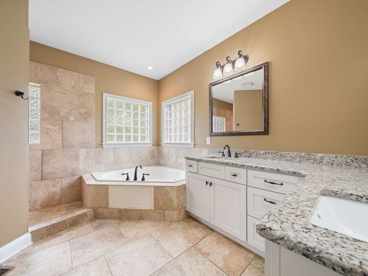 Primary bath featuring dual vanities, soaking tub, and separate shower.