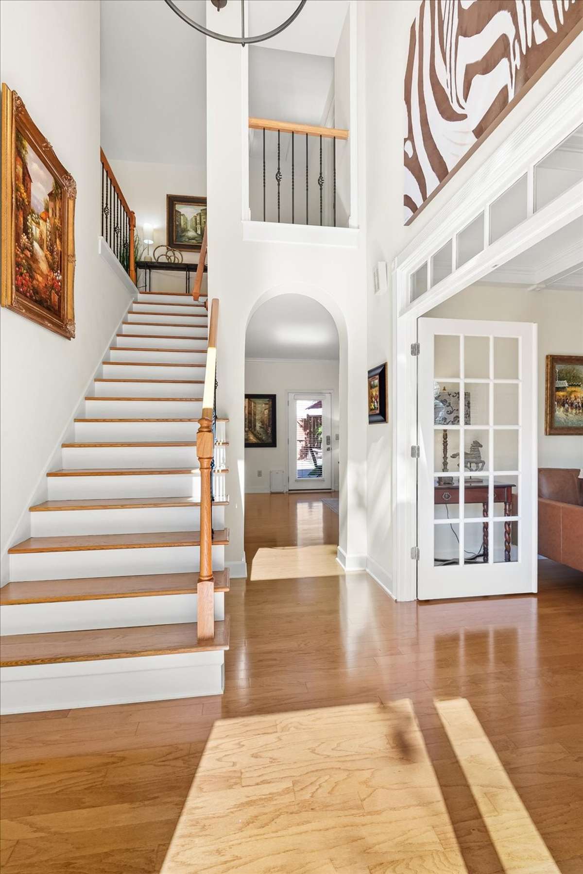 The front foyer features a beautiful picture window that fills the space with natural light, with a view into the parlor framed & a charming curved archway