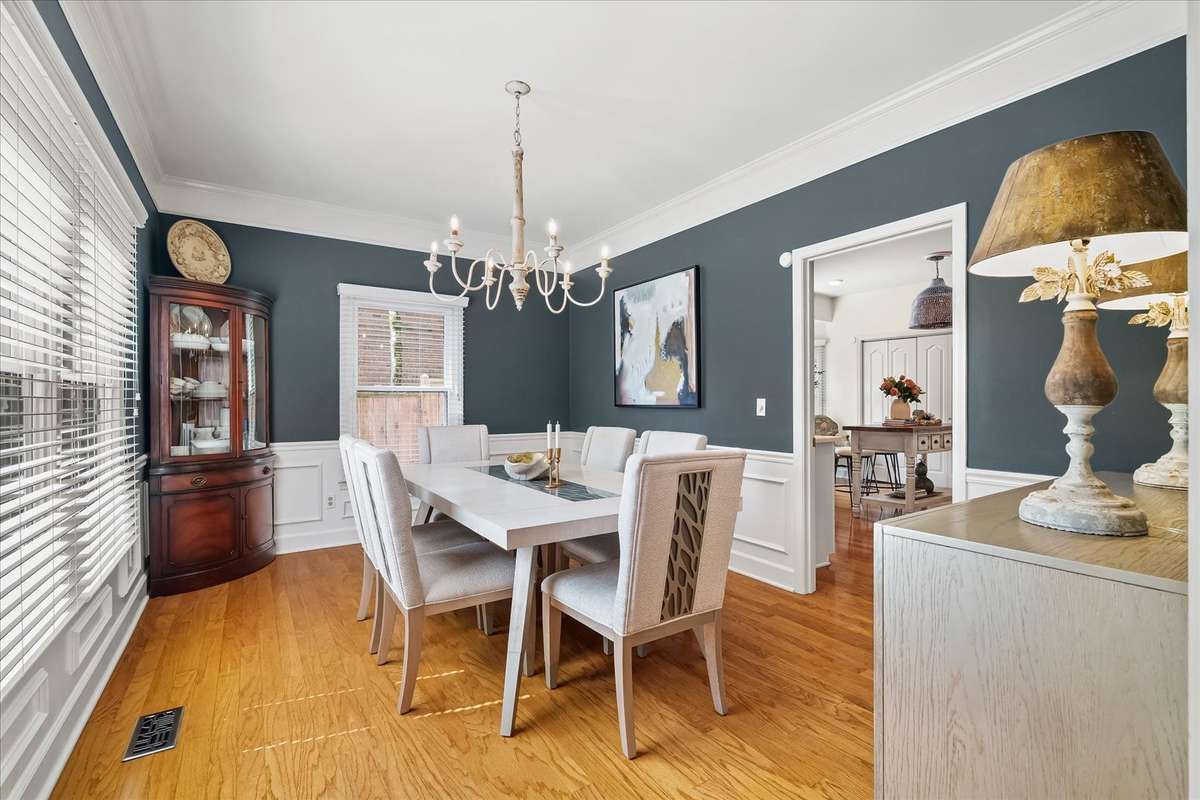 Formal dining with wainscoting, designer lighting, and plenty of room to host—hey takeout deserves a proper setting too.