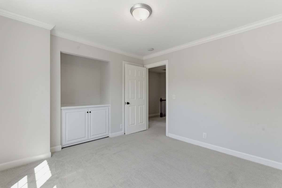 Second upstairs bedroom features a built in cabinet with open storage above.