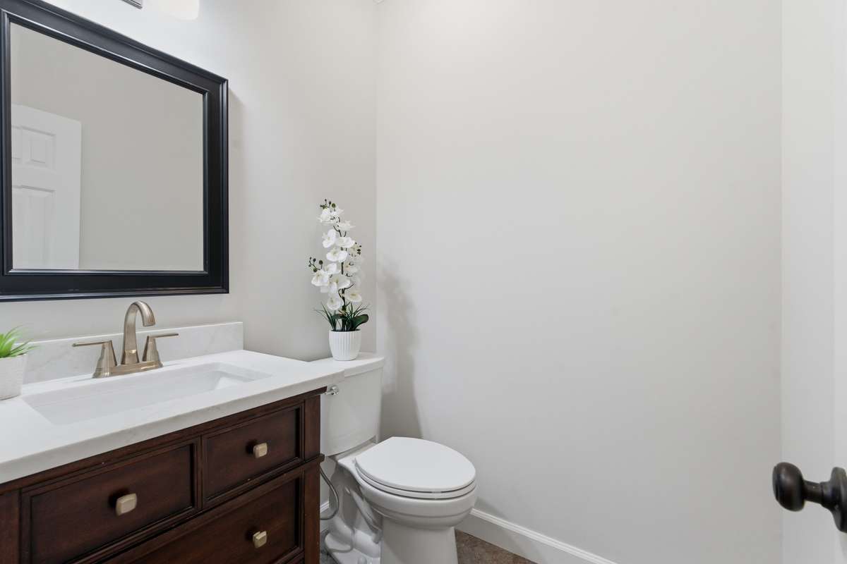 Main level half bath featuring new faucets, countertops and toilet.