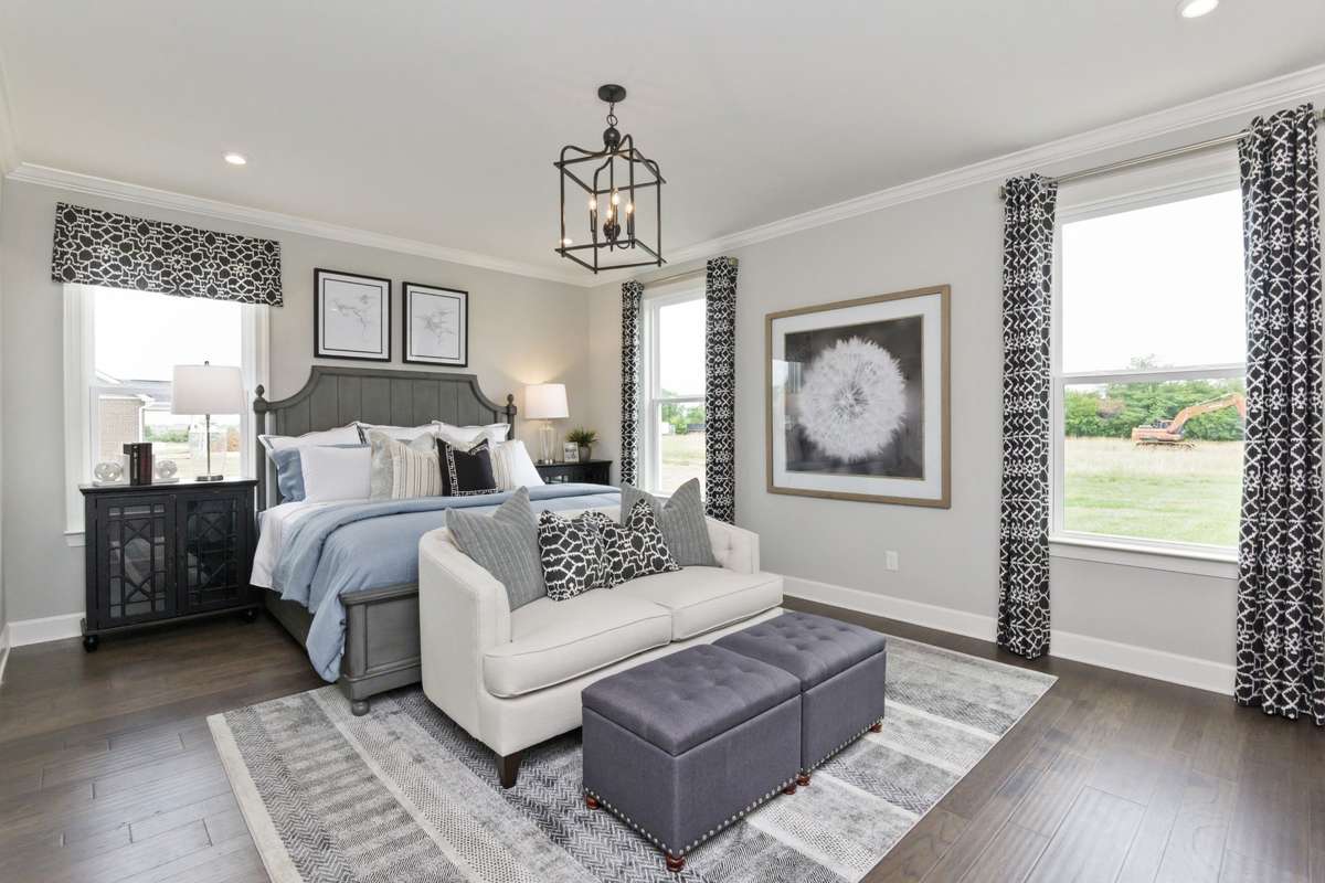 Oversized primary suite downstairs boasting with natural light! King size furnishings shown here. Photos are of model home.