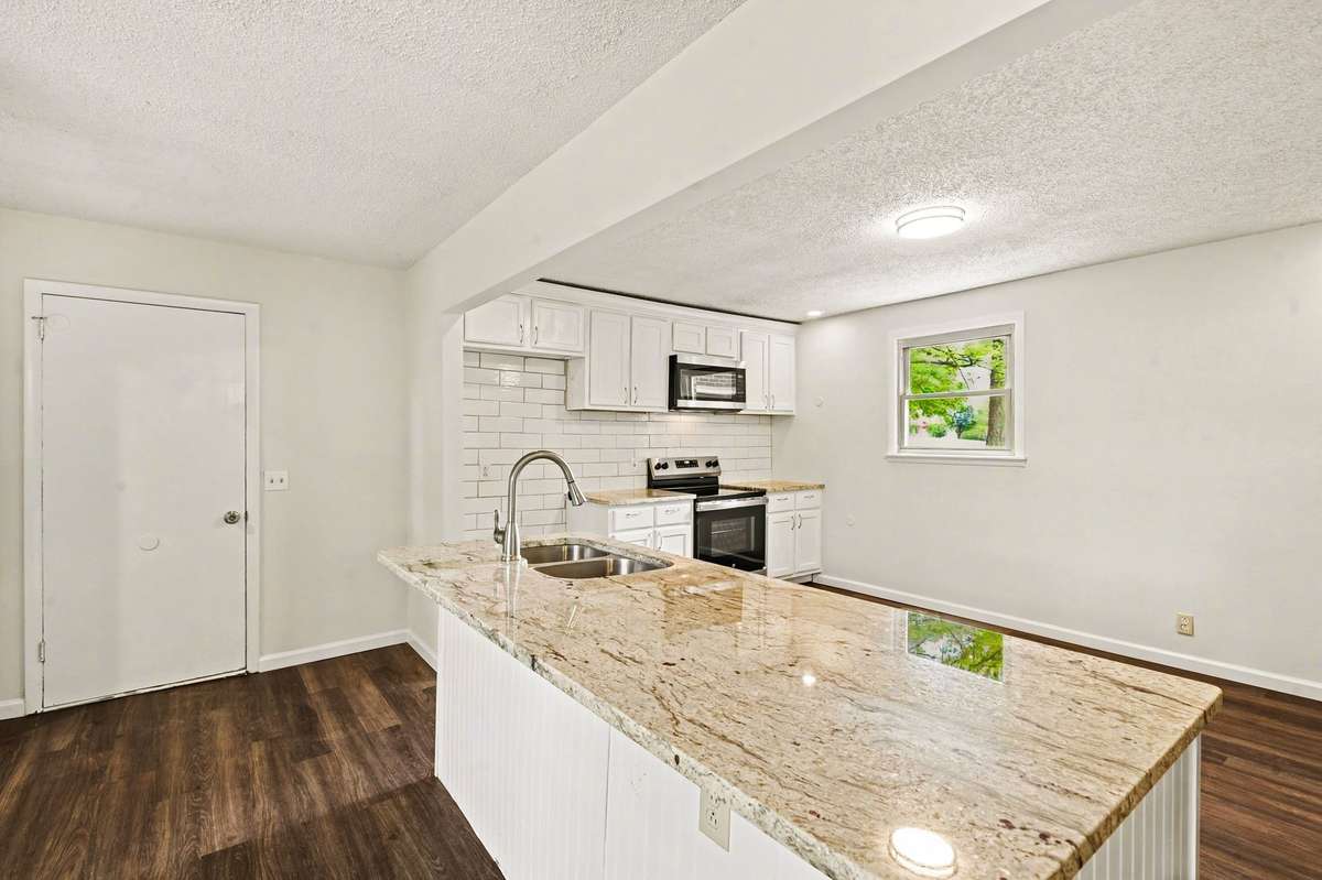 The wide kitchen island features room for up to four seating spaces, note the beautiful countertops and the green views out of every window!