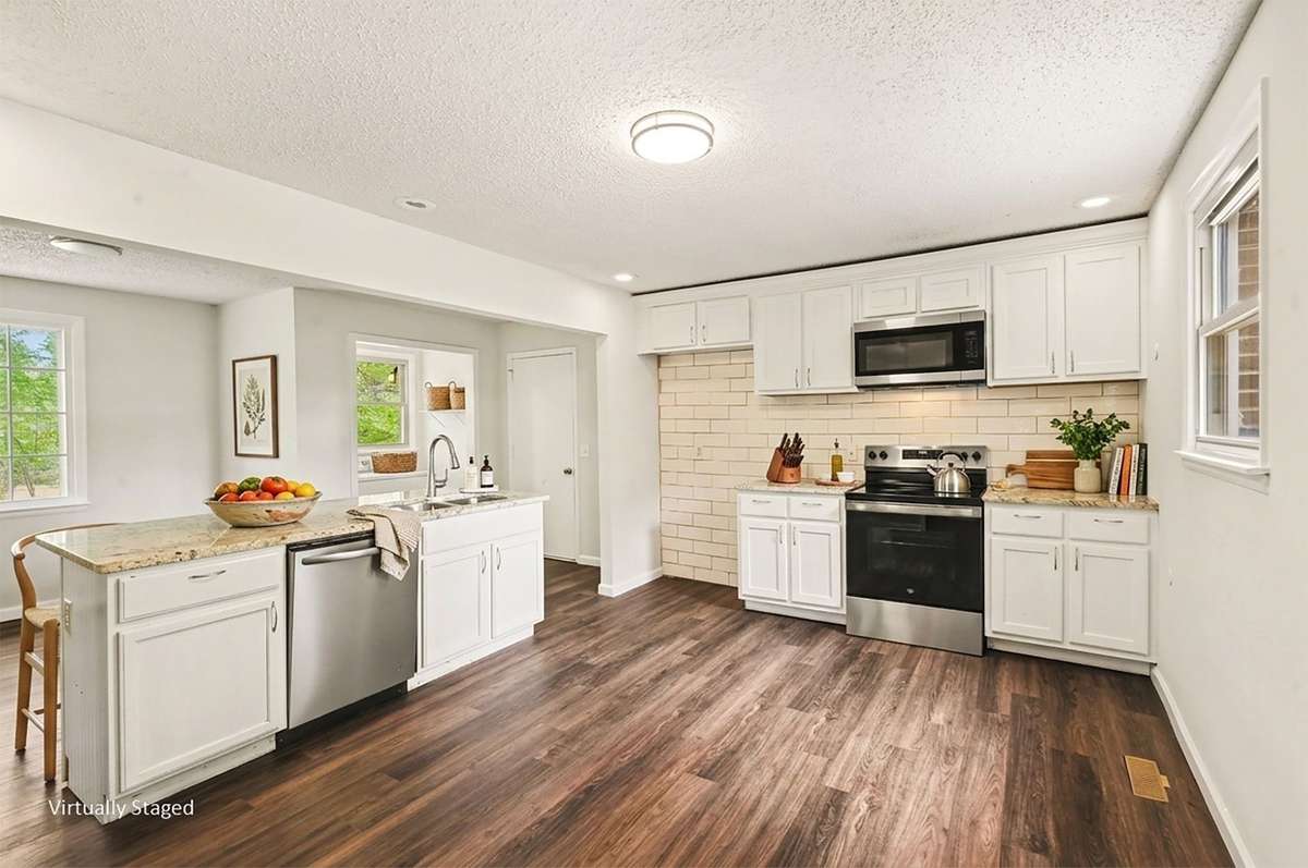 The kitchen features newer stainless steel appliances, stone countertops, white painted wood cabinets, custom tile backsplash and a kitchen island big enough for bar stools! There is ample room to add more cabinets, shelves or prep space!