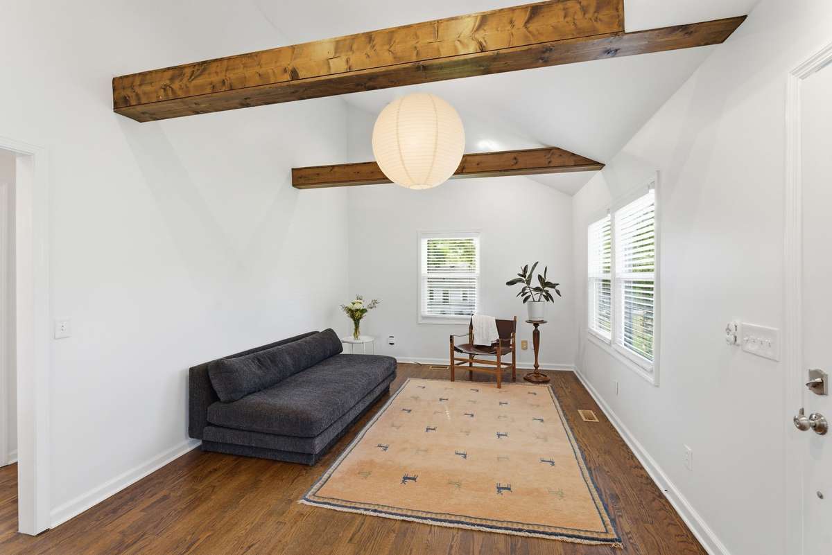 Open concept living room with vaulted ceiling and wooden beams.