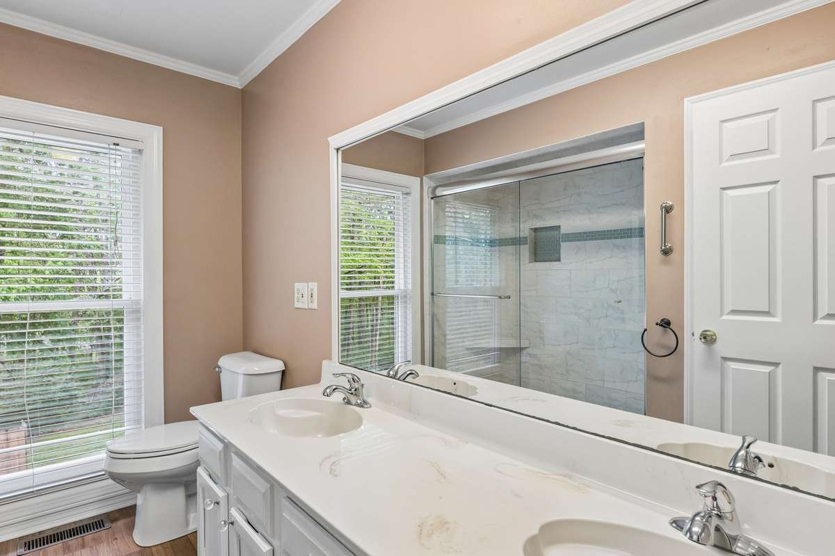 The primary bathroom is complete with a double vanity and a large, tiled shower.