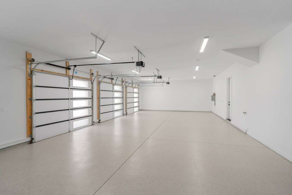 Oversized three car garage featuring three 10' x 10' doors and epoxy floor with EV charger plug in place. This space will easily accommodate three LARGE SUVs.