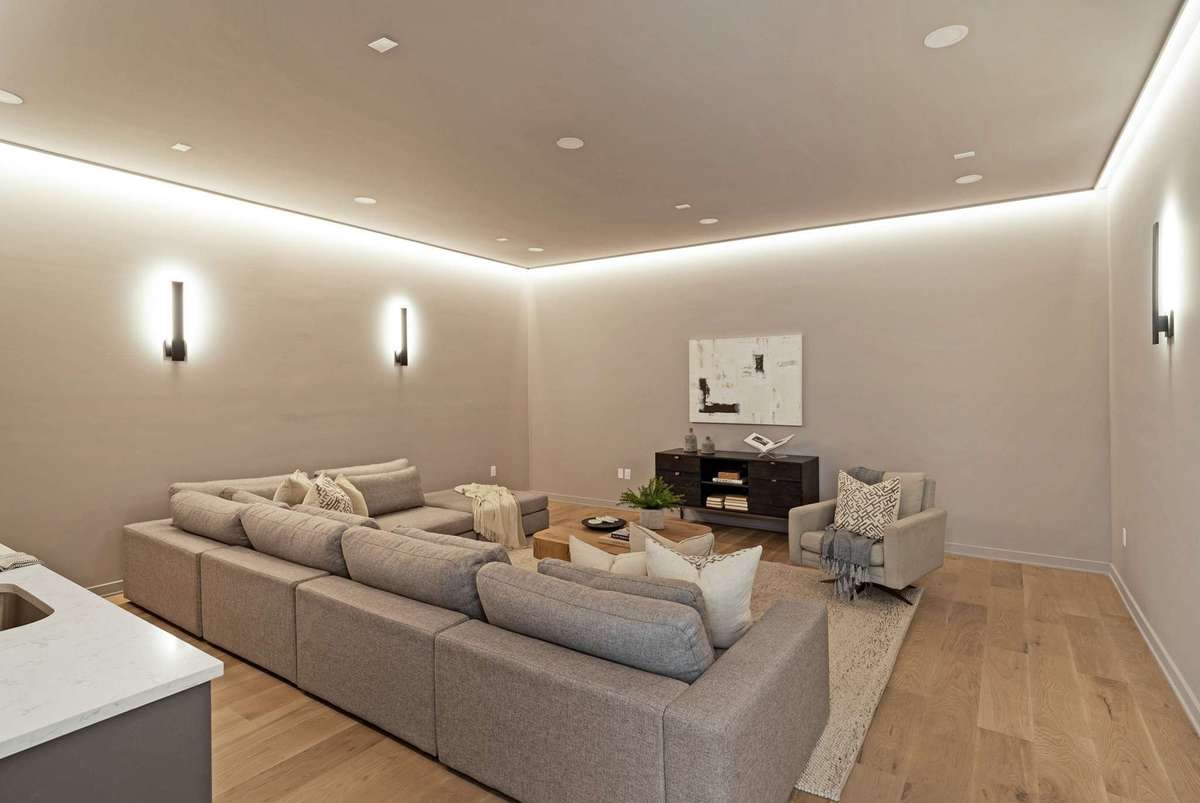 The theater room featuring LED ceiling feature light and wall sconces for the perfect movie and sports experience. The wall will easily support a 115" TV.