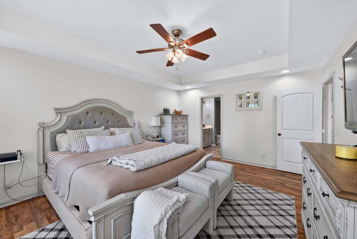 Luxury primary suite with hardwood floors, trey ceiling and a walk-in closet