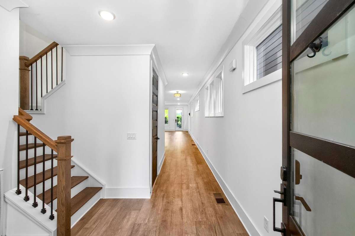 Graceful sightlines extend from the polished entry hall to the glass-panel door and windows at the rear of the house.