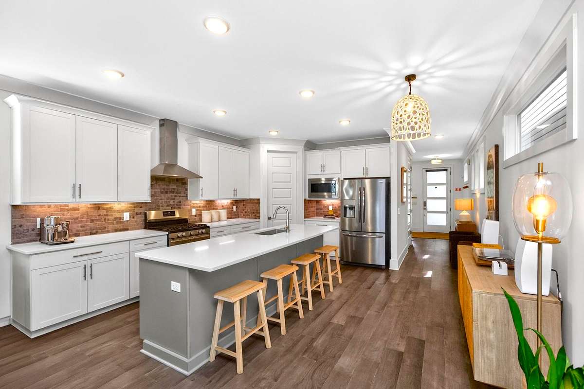 A gorgeous tile backsplash, gleaming quartz countertops, and crisp white cabinetry distinguish this beautiful kitchen.