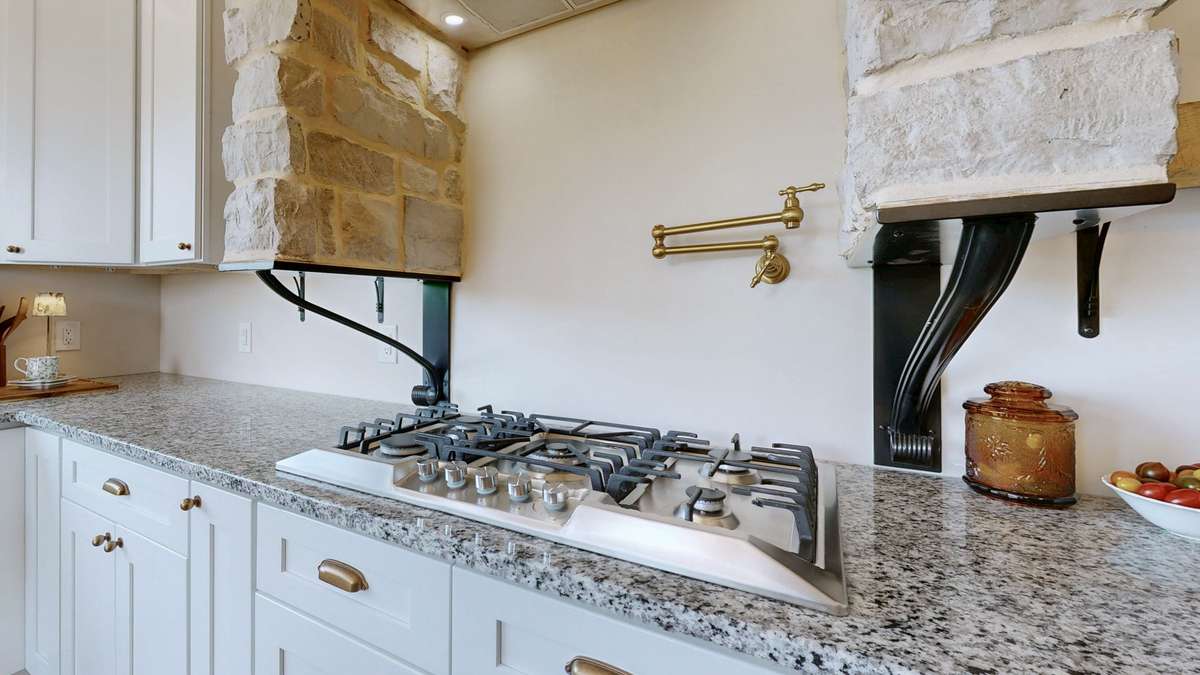 This is a view of the gas cooktop, the pot filler, the vent, and lights above the stove.