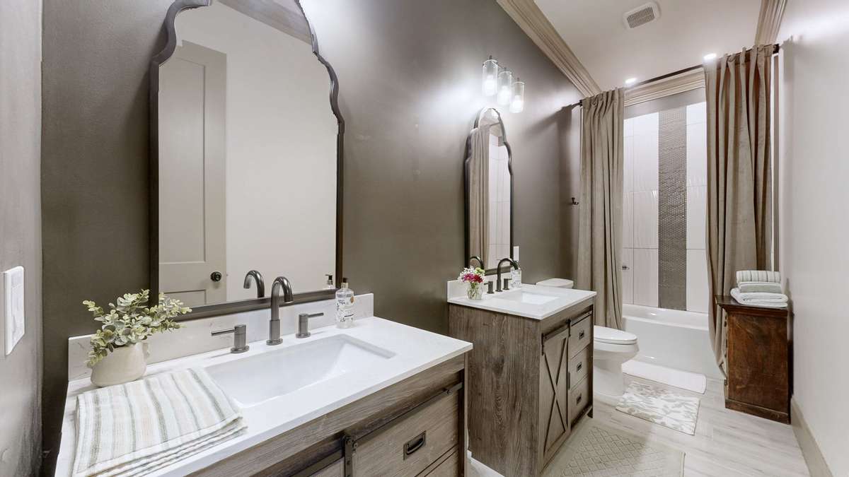 This is Bathroom #2  which has double vanities, toilet, and a bathtub/shower combination.
It has tile up the sides of it also.