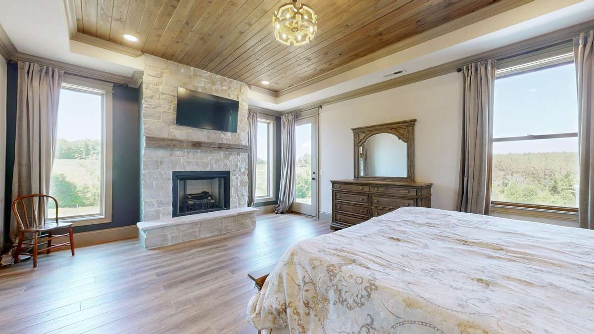 This is the Beautiful Master Bedroom with gorgeous shiplap ceilings, stone fireplace that is gas, lots of windows for light, a door out to the patio.   Amazing Room.