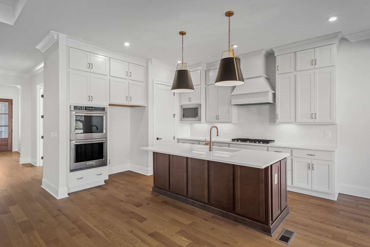 A crisp white Kitchen with the warm toned cabinets of the island.