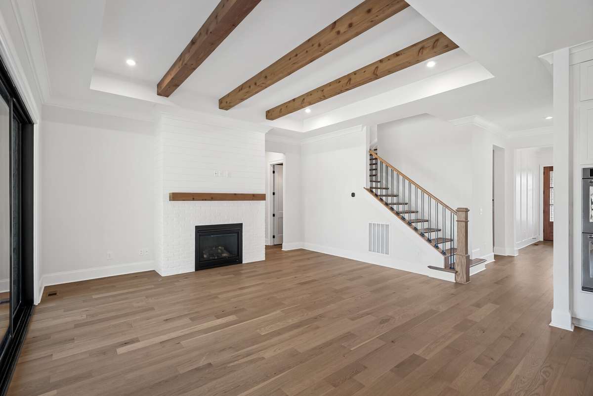 White brick fireplace with cedar mantle which matches the cedar beams in the ceiling.