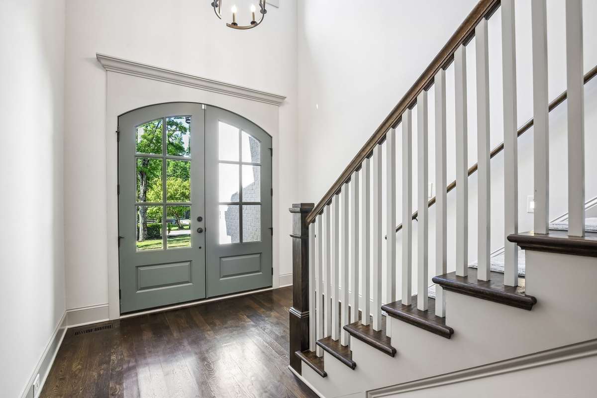 Light-filled entry with staircase, detailed trim, and hardwood floors