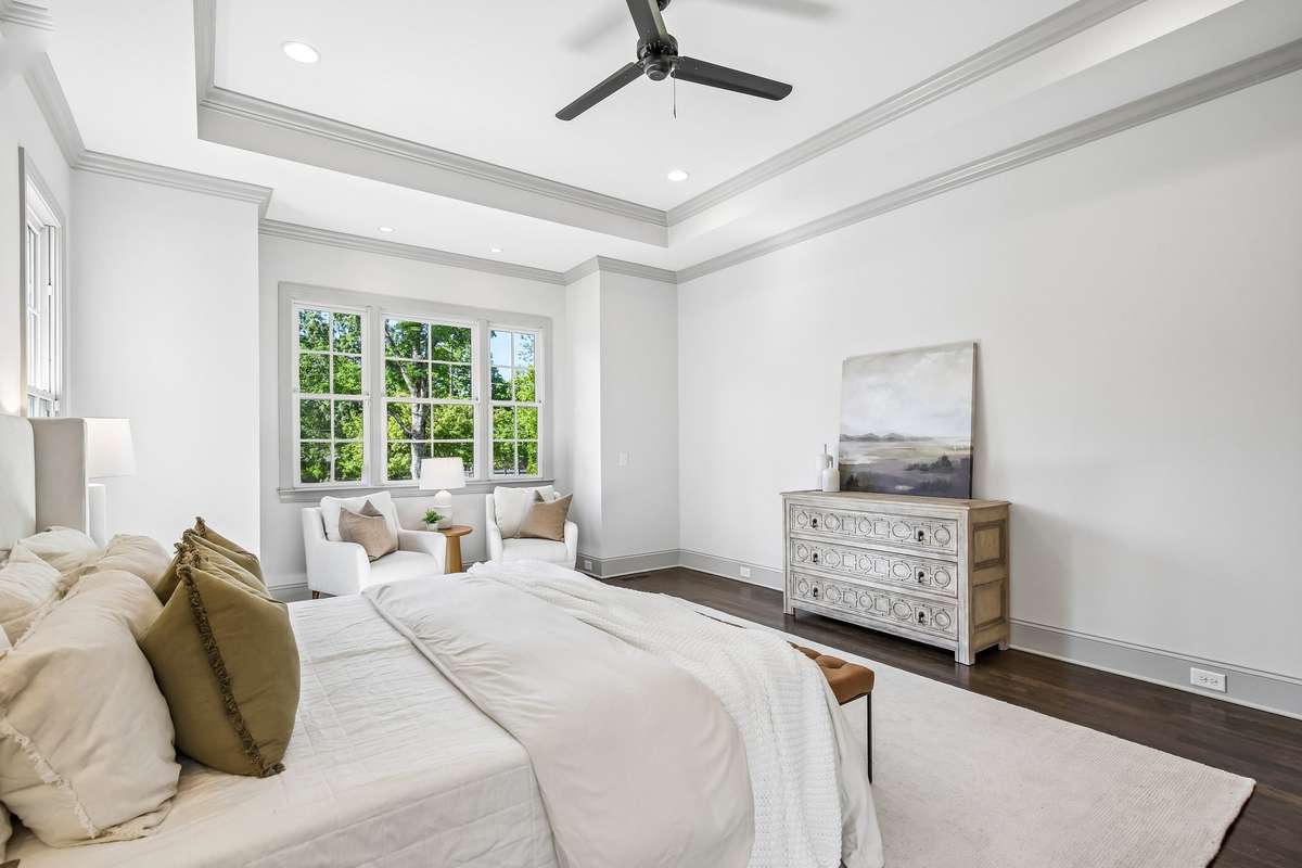 Primary bedroom with tray ceiling and large windows