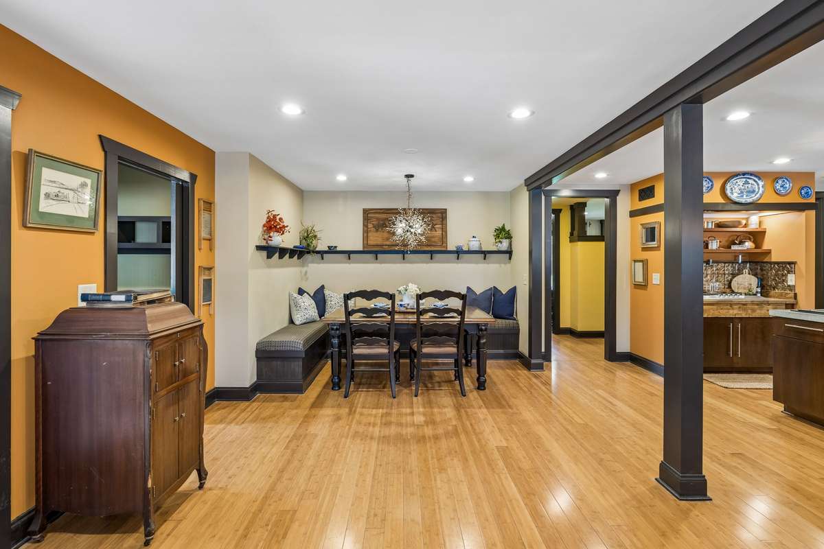 Dining area with built-in bench seating, custom shelving, and statement lighting. Open layout connects effortlessly to the kitchen, highlighted by hardwood flooring and rich trim details for a warm, welcoming atmosphere.