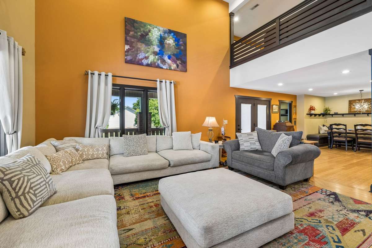 Spacious living room with soaring ceilings, oversized sectional seating, and abundant natural light, creating a warm and inviting gathering space.