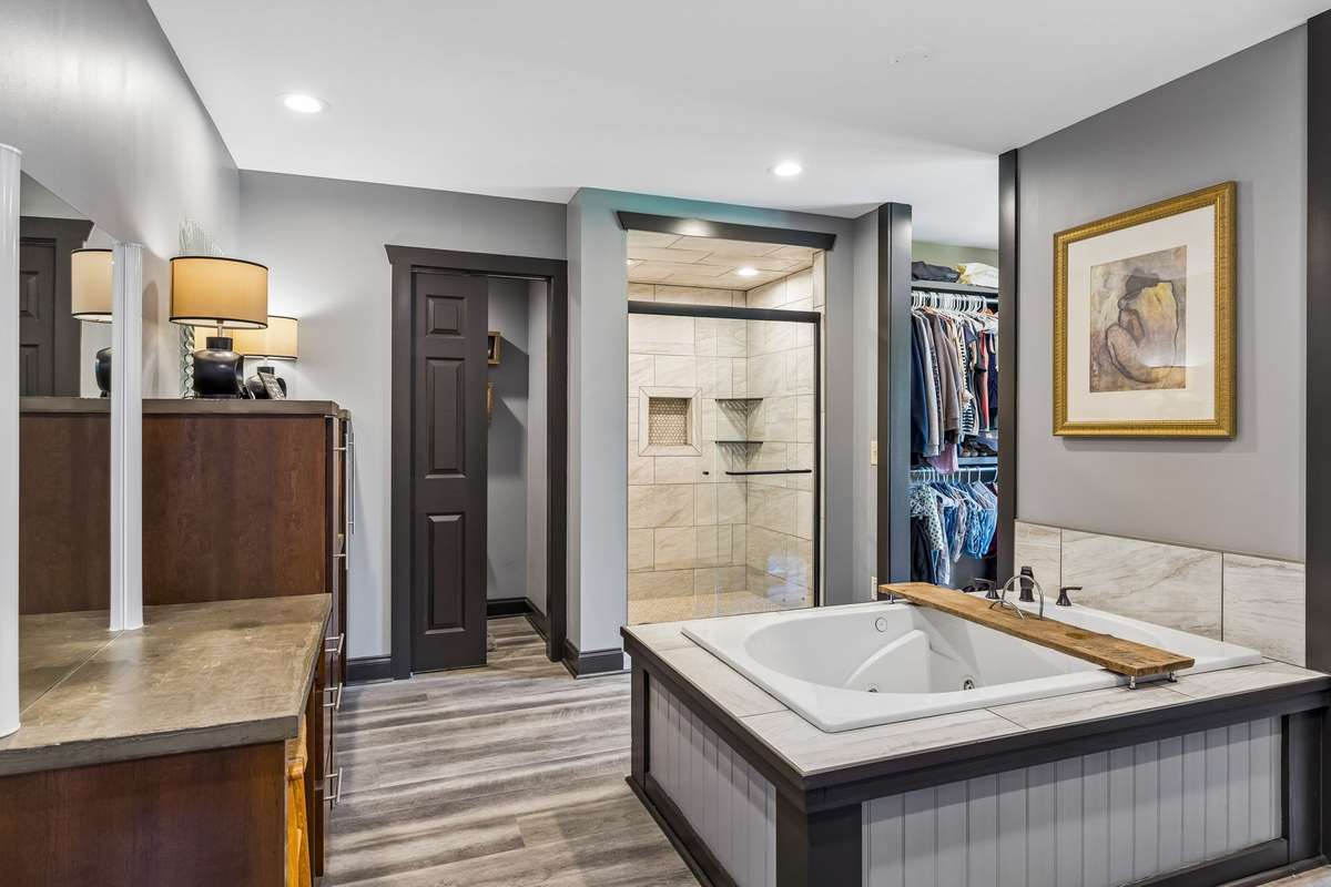 Spa-like primary bathroom featuring a large soaking tub, dual vanities, and a beautifully tiled walk-in shower with glass enclosure.
