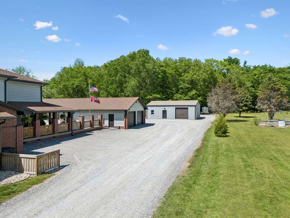 Long drive leading to the home and large detached shop, offering ample parking and easy access for vehicles, equipment, or guests.