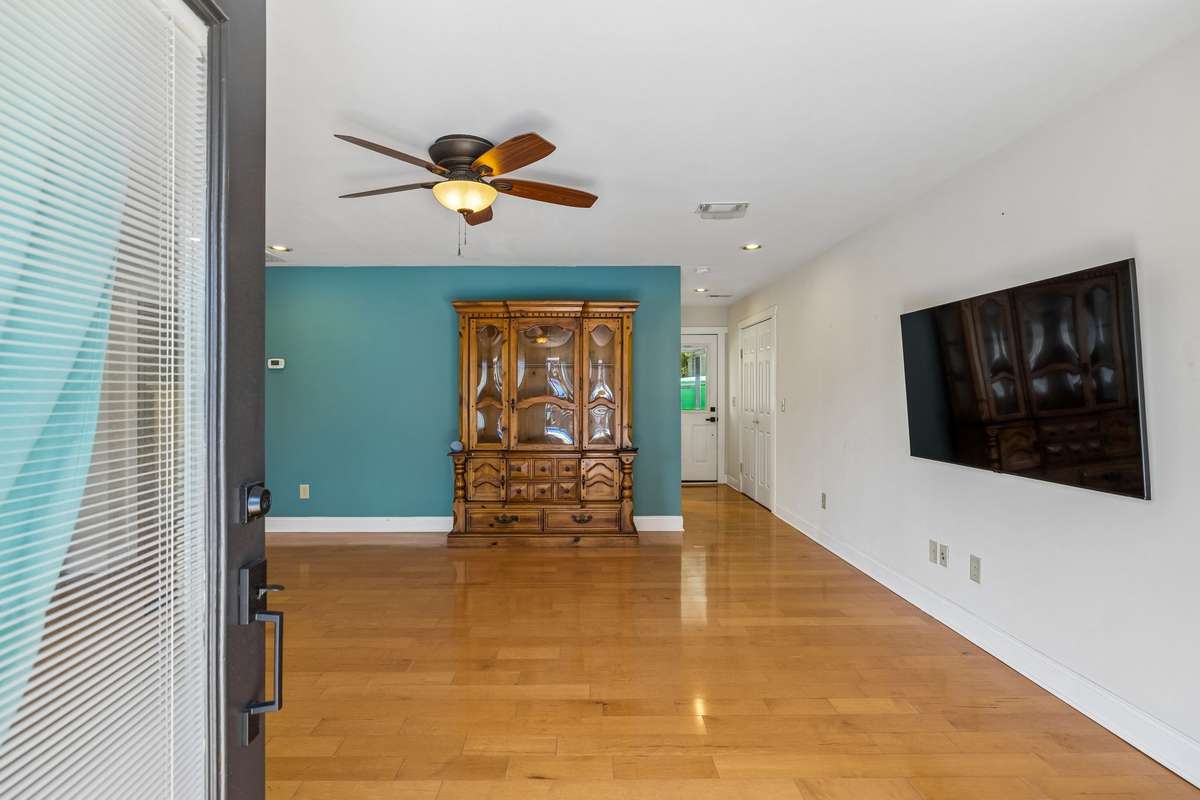Guest house Expansive living area highlighted by accent wall, mounted TV space, and easy access to adjacent rooms.