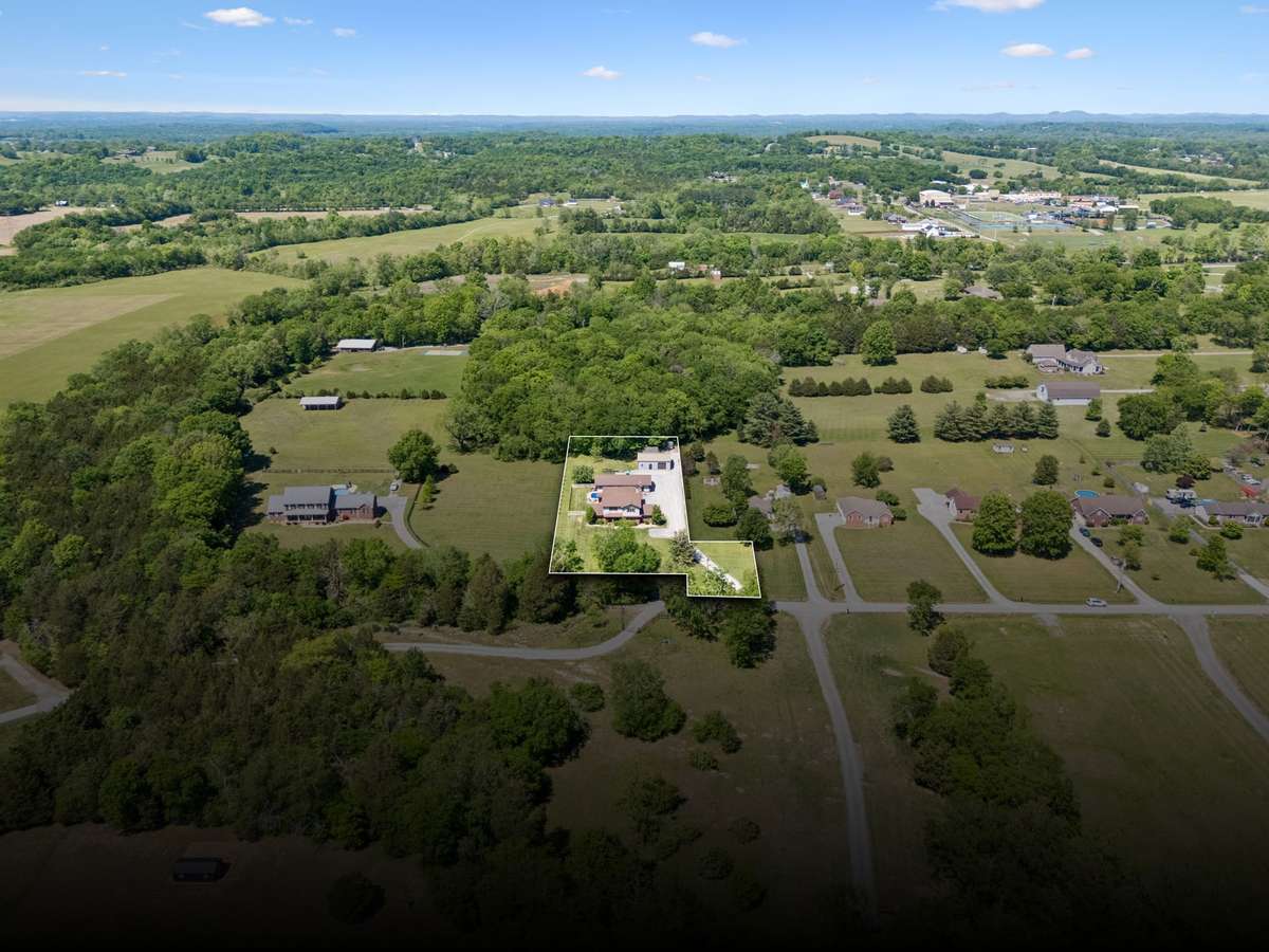Wide aerial view with property boundaries highlighted, showing acreage, privacy, and surrounding landscape.