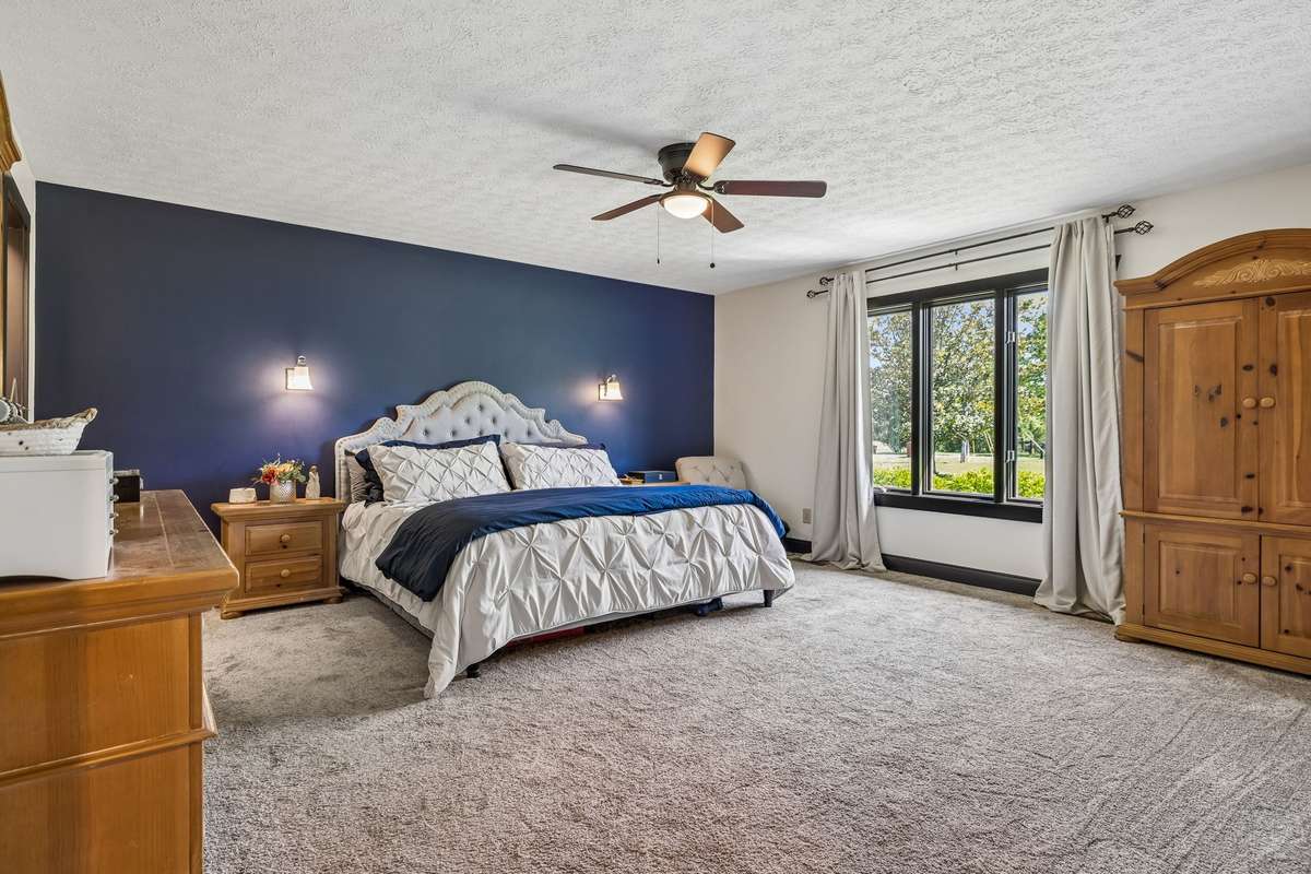 Generously sized primary bedroom with plush carpeting, statement accent wall, and plenty of space for additional furnishings.