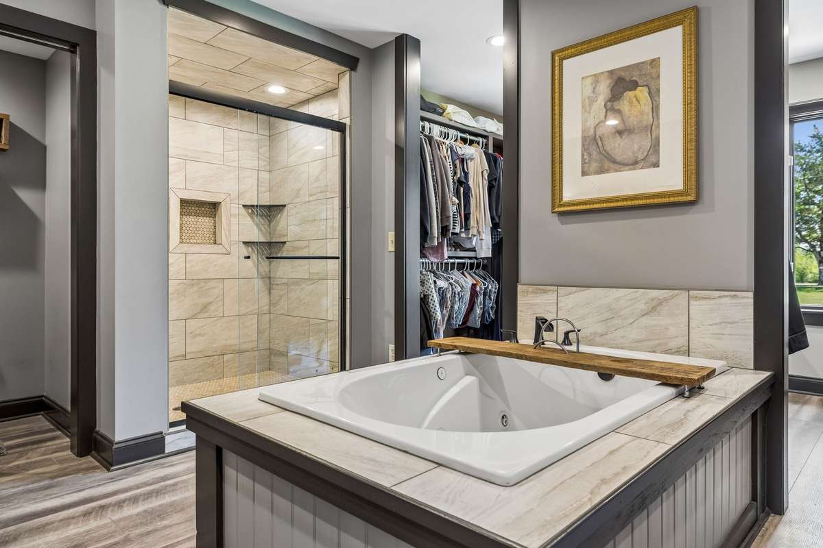 Another view of the luxurious primary bath highlighting the custom tile work, walk-in shower, and direct access to the closet.