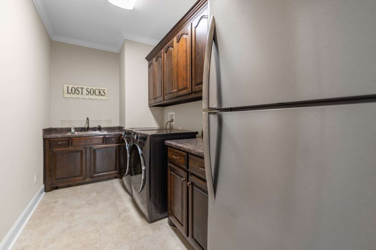 Off the mudroom is a spacious utility room with sink, refrigerator and washer dryer combo.