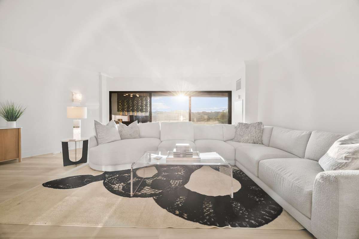 The living room enjoys beautiful vistas through the three-door opening onto the expansive outdoor balcony.