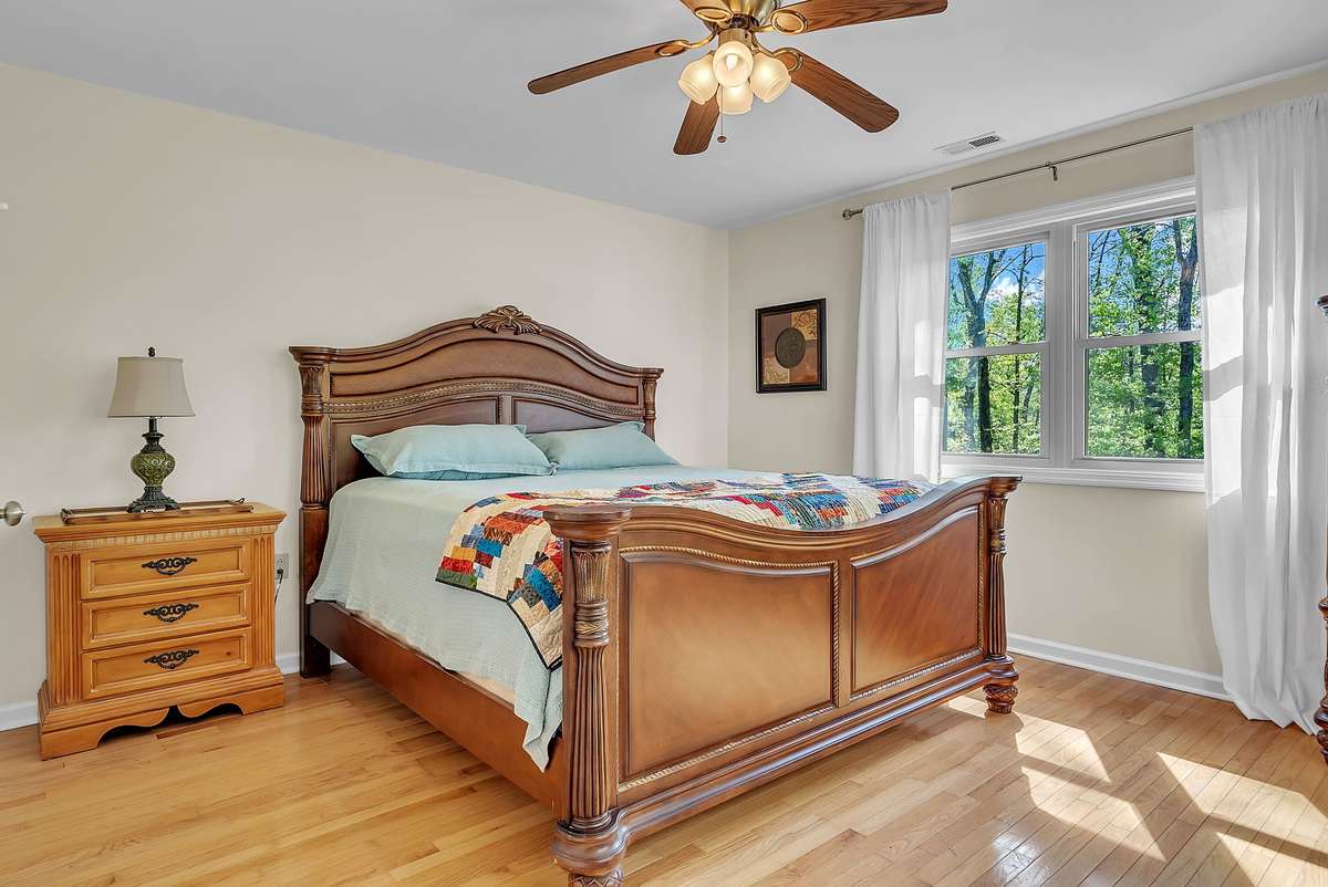 Mother-in-law apartment: Peaceful bedroom in the mother-in-law quarters featuring a large king bed, hardwood floors, ceiling fan, and big windows with wooded views. Private retreat with easy access through the garage.
