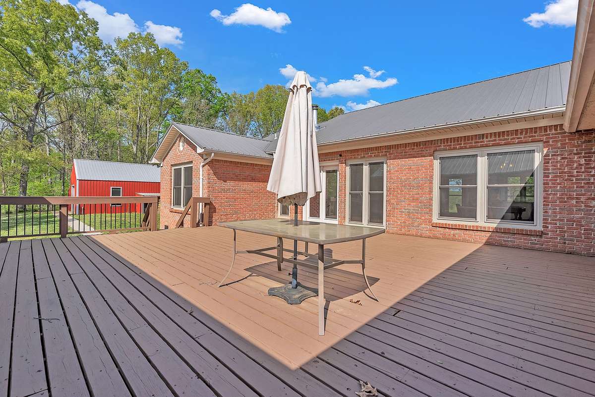 Picture family gatherings around this large outdoor table under the shade of a market umbrella, with the red barn as your scenic backdrop. The deck wraps the home beautifully and offers multiple seating zones for entertaining.
