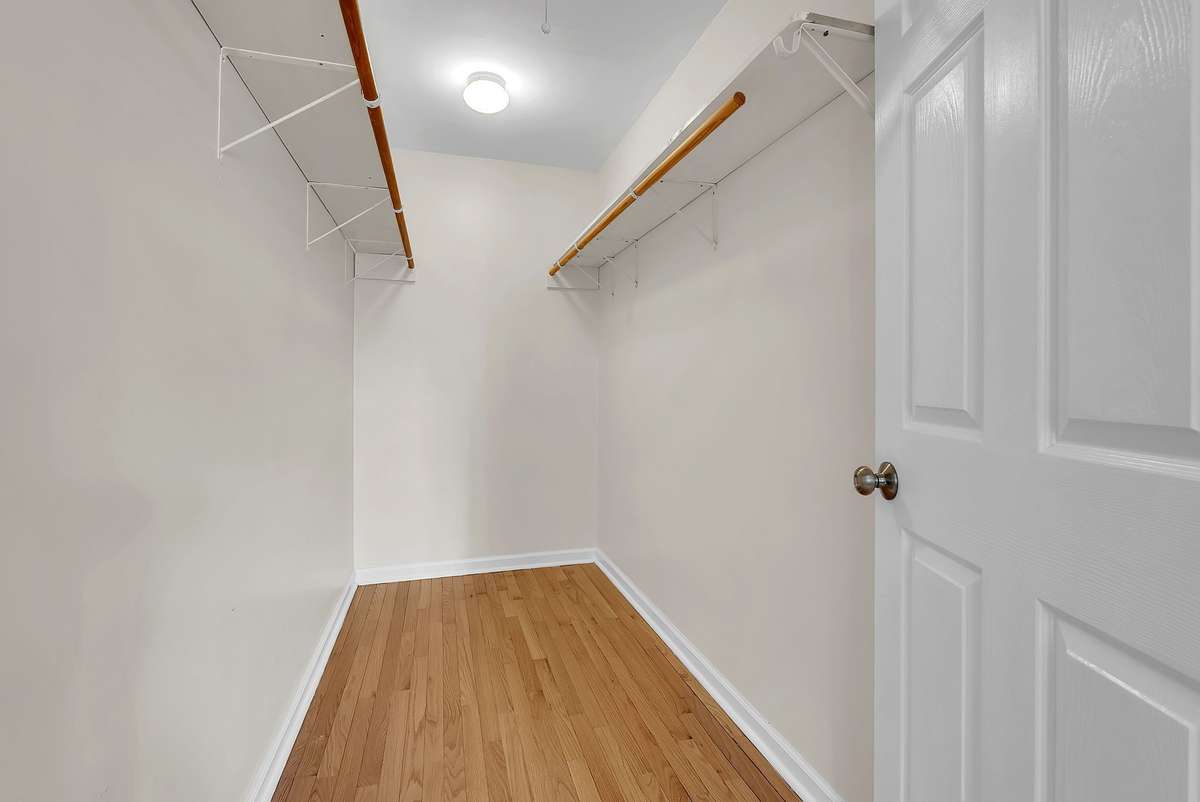 Mother-in-law apartment: Spacious walk-in closet inside the mother-in-law apartment with white shelving, hanging rods, and overhead lighting. Ample storage for clothing, linens, or seasonal items in this private suite.
