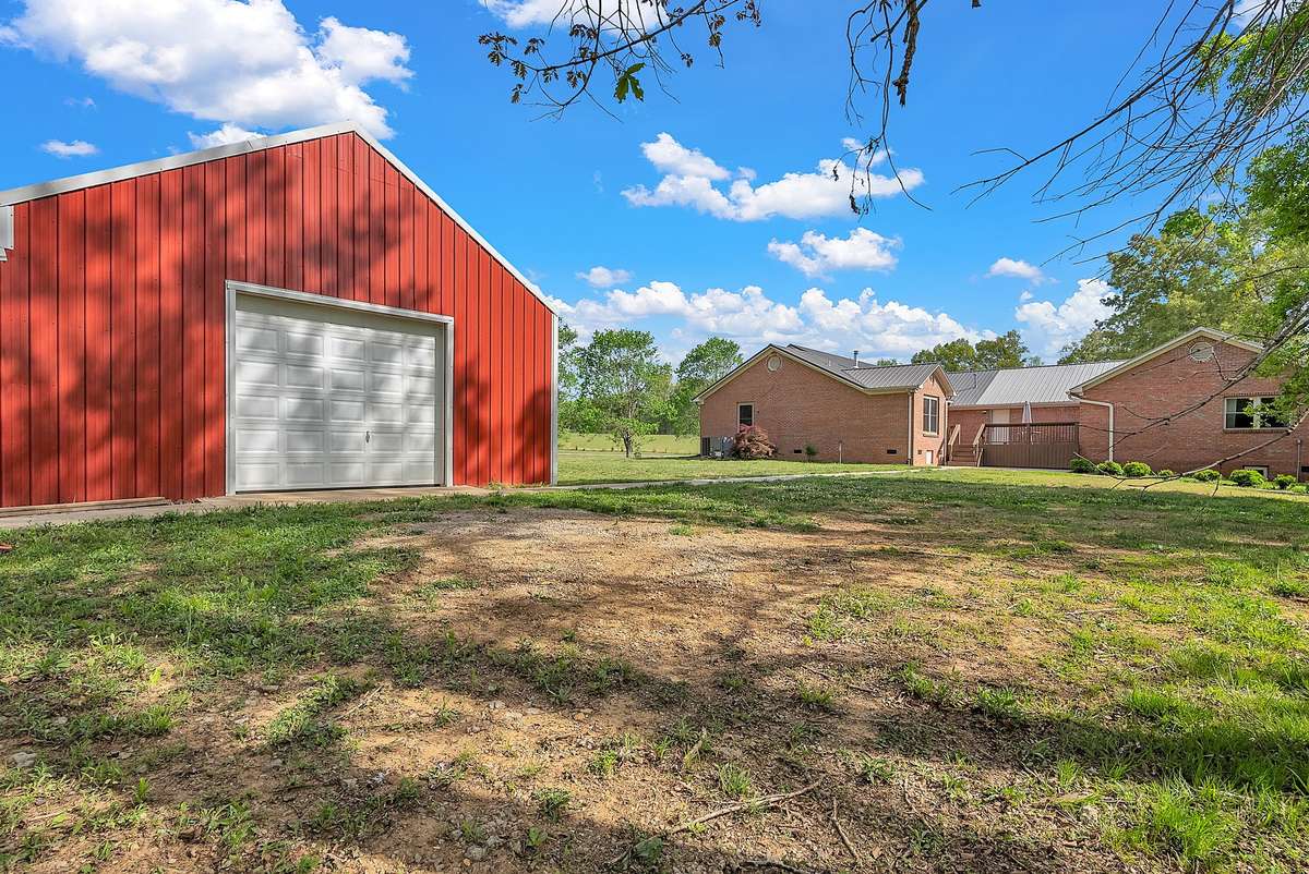 Built in 2021 with sharp red and white metal siding, this versatile barn features a lean-to with fenced area for chickens or small livestock, concrete floor, 220-amp outlet, dedicated storage, and a loft with stairs and lighting.