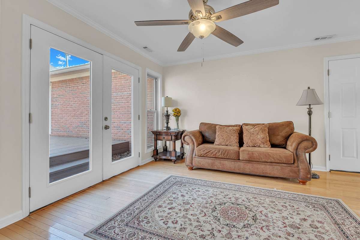 Mother-in-law apartment: Cozy living area in the attached mother-in-law quarters with brown leather sofa, ceiling fan, French doors to the deck, and beautiful hardwood floors. Bright and welcoming space for relaxing or entertaining.