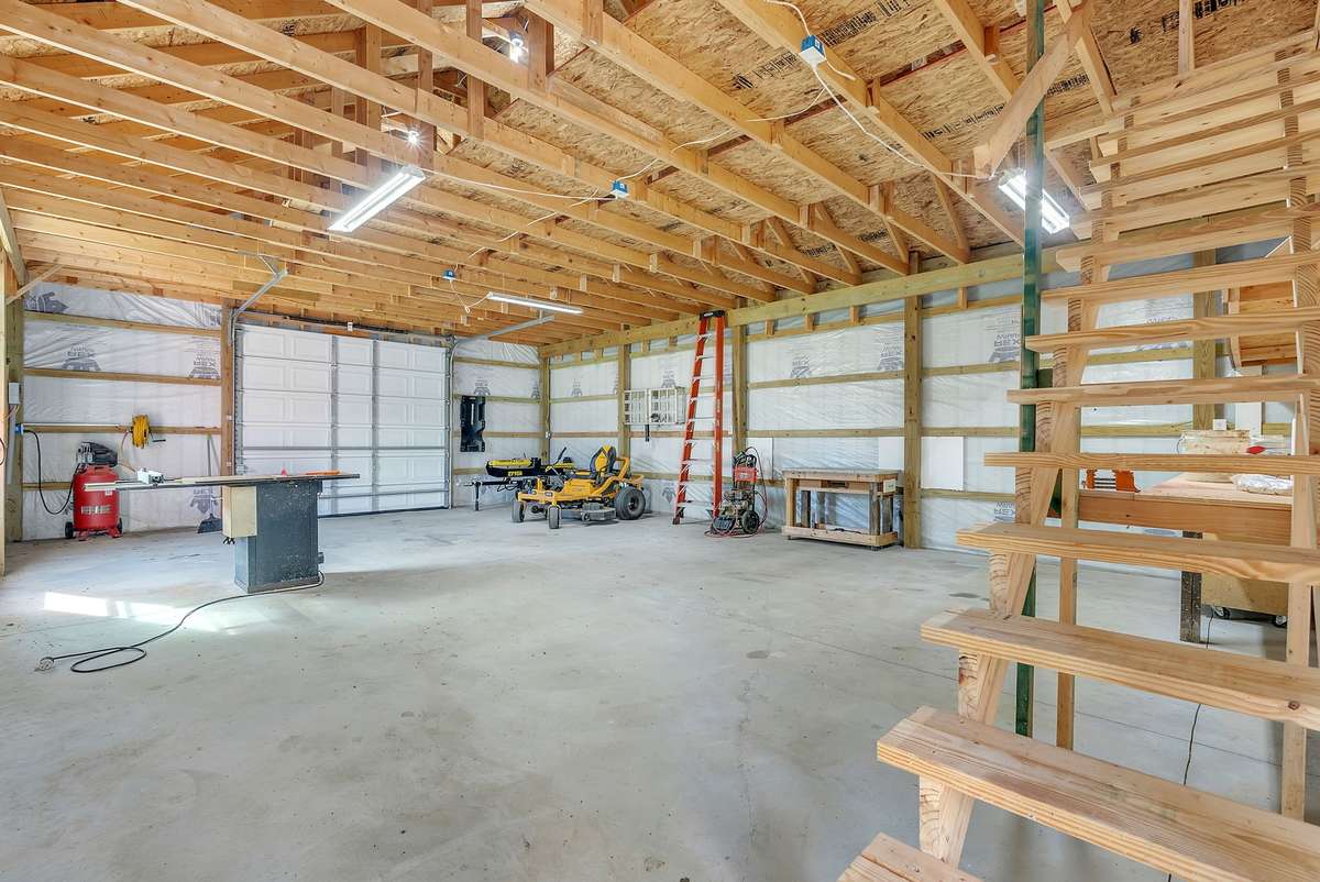 Includes concrete floor and 220-amp outlet. Dedicated storage accessed by stair to loft. Workbenches and shelving. Temperature-controlled attic fan.