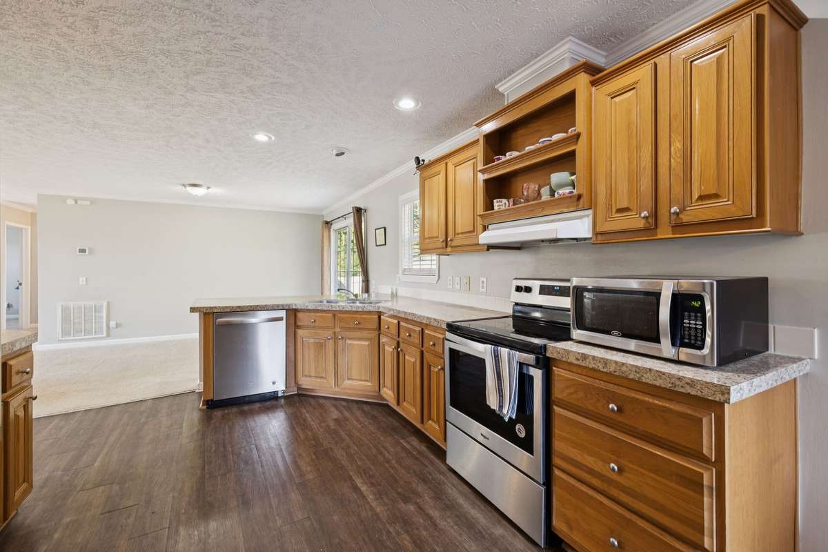 This kitchen features warm wood cabinetry, stainless steel appliances, and generous counter space with an open layout that connects seamlessly to the living area—perfect for everyday cooking and entertaining.