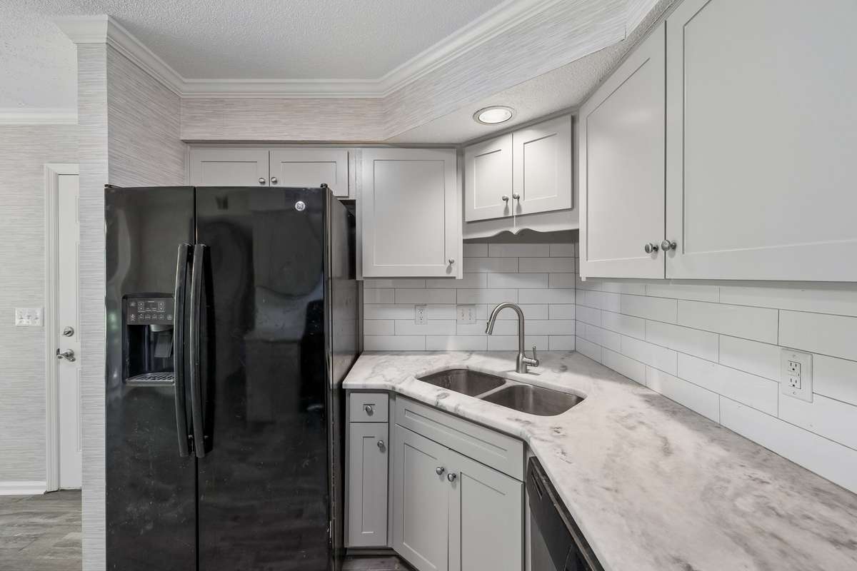 A closer view of granite countertops and fridge that remains with house. A microwave will also remain in the house. It is currently stored in the laundry room that adjoins the kitchen.