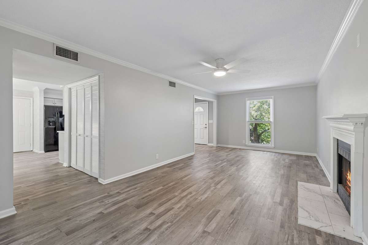 A view from the end of the backyard side of the living facing facing toward the front of the house. The hallway to the left goes past the half bath and laundry room into the kitchen.
