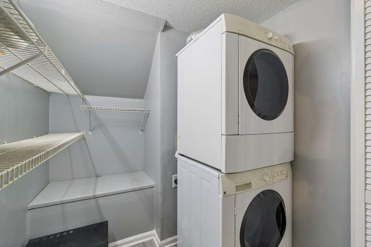 This washer/dryer unit remains with the house. Microwave is partially shown on bottom left. There's plenty of shelving for laundry and household cleaning supplies.