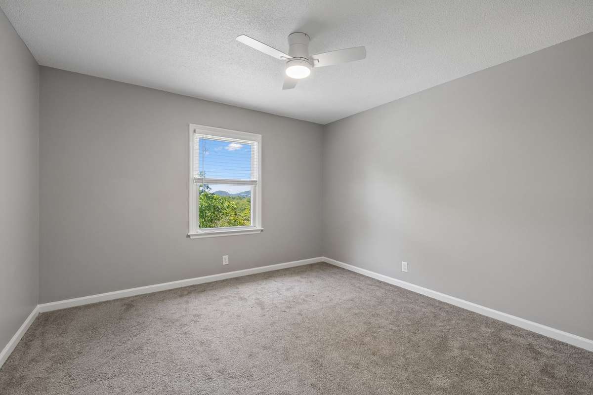 The third bedroom upstairs looks out to the front yard and, beyond, to beautiful trees and sunsets. Note new ceiling fan and newer carpeting.