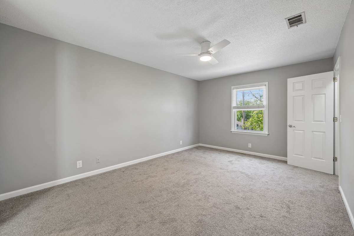 The primary bedroom is upstairs. This view faces to the front  yard. Note the newer carpeting and new ceiling fan. The door shown on the top right of the photo goes into a walk in closet.